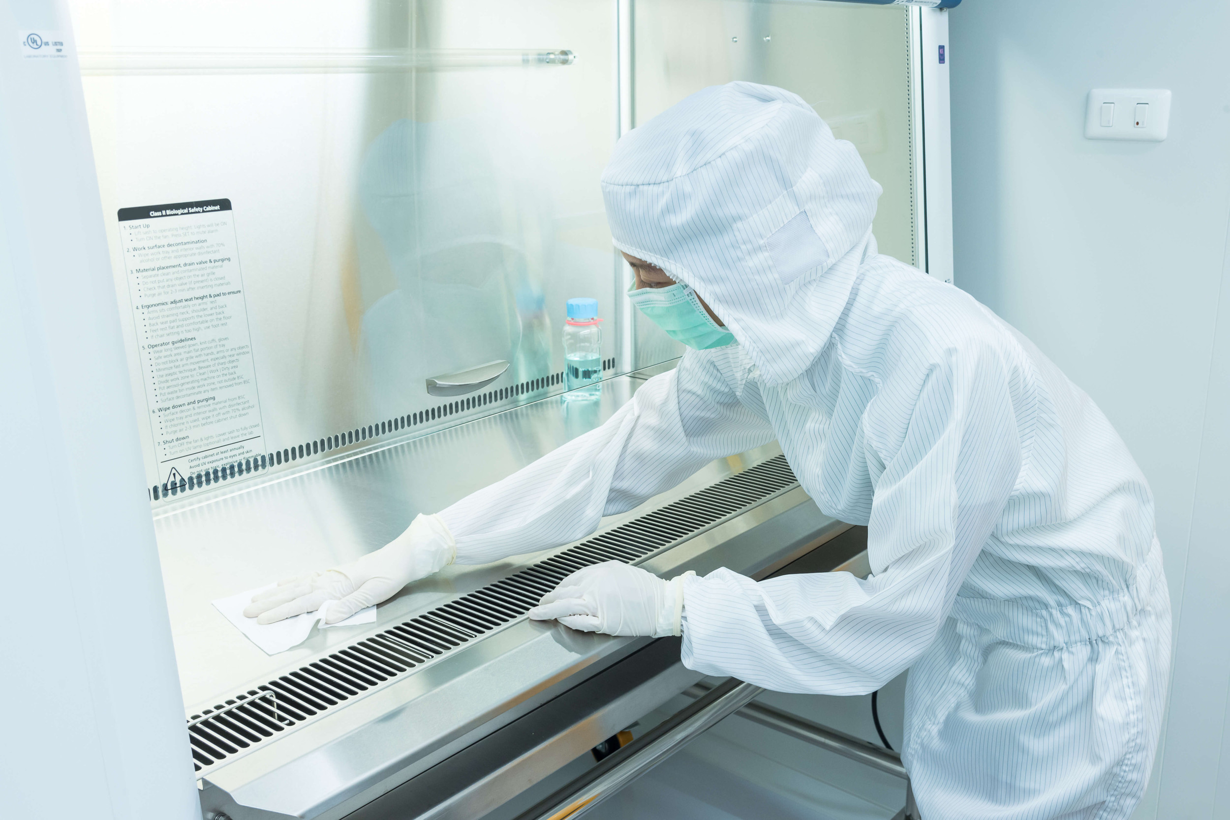 Technician wiping down a biosafety cabinet work surface